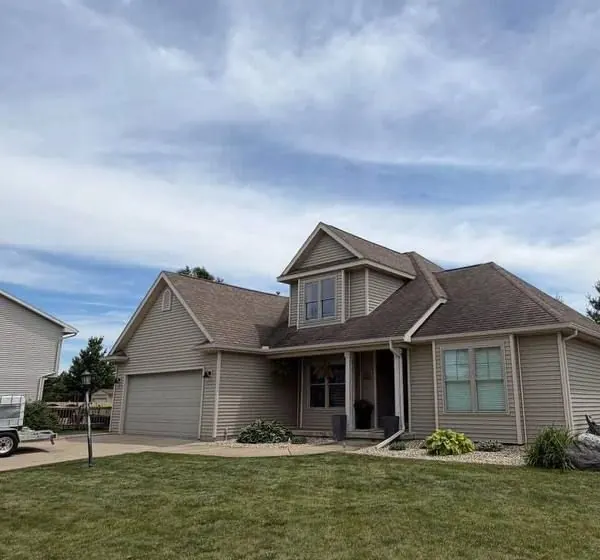 Two-story home with tan vinyl siding and a front lawn in central Illinois