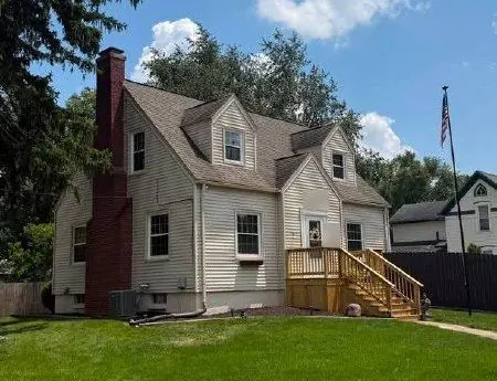 Story-and-a-half home with light siding and a wooden front deck and steps